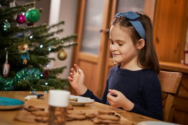 Tatlı kız zencefilli ekmek yapıp süslüyor.