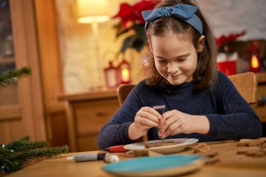Tatlı kız zencefilli ekmek yapıp süslüyor.