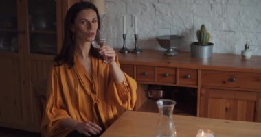 Sarı bluzlu güzel kadın masada su içiyor.