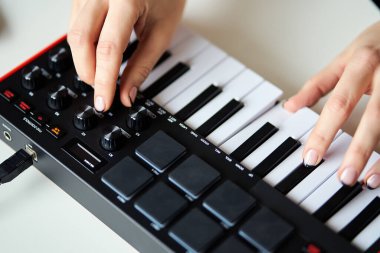 Küçük bir modern müzik sentezleyicisi çalan kadın.