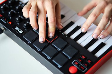 Küçük bir modern müzik sentezleyicisi çalan kadın.