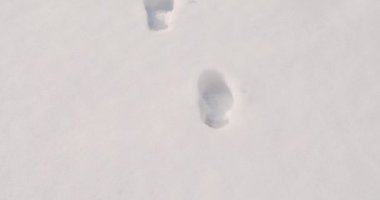 Beyaz karda derin ayak izleri. İnsan ayak izlerini takip ederek.