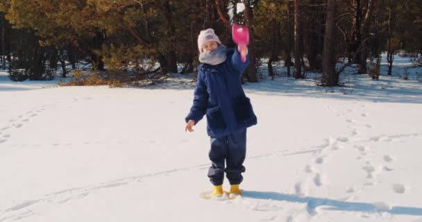 Мила дівчина будує і грає на снігу в лісі — стокове відео