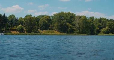 Nehirdeki motorlu tekne ve kıyı manzarası yavaş çekimde.