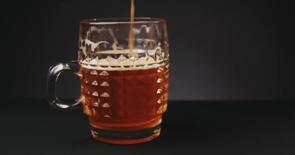 Pouring beer into glass over dark background. Slow motion — Stock Video