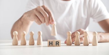Tahta insan figürü tutan bir adam. Tahta küplerle ilgili İK sözcüğü. İnsan Kaynakları
