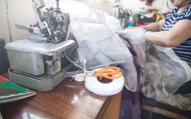 Masada makas var. Kafkasyalı terzi dikiş makinesiyle çalışıyor..