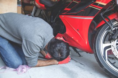 Beyaz adam garajda motosikletini tamir ediyor..