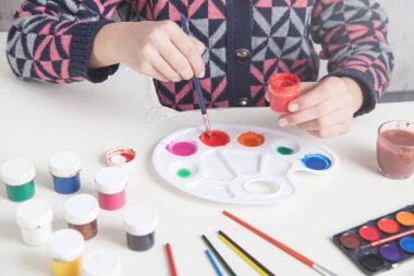 Tablolar masanın üstünde. Boyacı fırçayı tutuyor. İş, Yaşam Tarzı