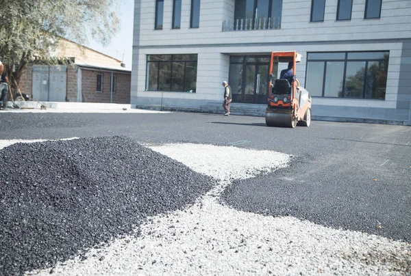 Asphalt roller stacking and pressing hot asphalt.