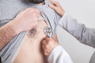 Doktor steteskop kullanarak hastanın kalbini kontrol ediyor..