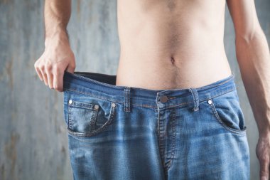 Büyük beden kot giyen bir adam. Kilo kaybı