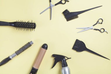  Sarı arkaplanda makas, tarak ve diğer saç şekillendirme araçları.