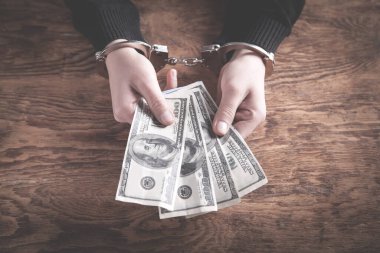 Elleri kelepçeli, ellerinde dolar banknotları var. Yozlaşma