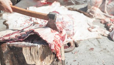 Taze et işleniyor. Elinde balta olan kasap eti ayırıyor.