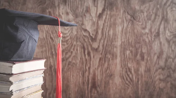 毕业帽 书架在木制背景上 — 图库照片