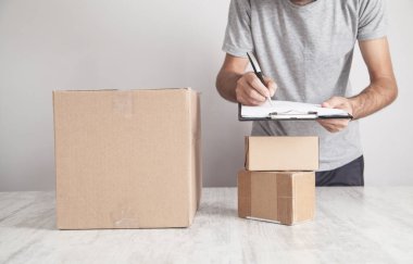Panoya yazı yazan adam. Masadaki karton kutular. Ürün, Ticaret, Perakende, Teslimat