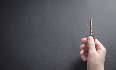 Siyah arka planda eski anahtarı tutan.