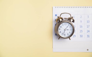 Sarı arkaplanda takvimi olan alarm saati.