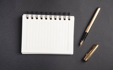 Siyah arkaplan üzerine kalem ve not defteri.