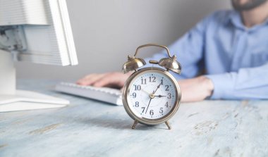 Masadaki çalar saat. Ofiste çalışan iş adamı.