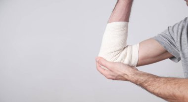 Dirseğinde elastik bandaj olan bir adam eli..