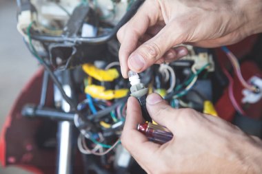 Motosikletteki ampulü inceleyen tamirci..