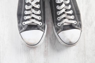 Beyaz masada bir çift eski kirli ayakkabı..