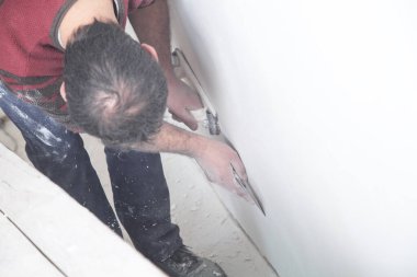 İşçi duvarı zımpara kağıdıyla öğütüyor. Yenileme