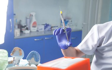 Diş muayenehanesinde şırınga tutan bir dişçi..