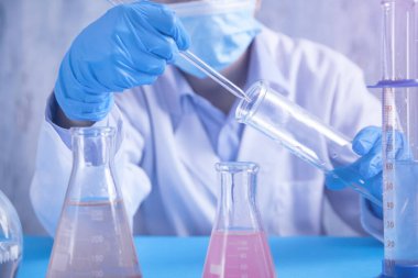 Laboratuvarda şişeyle çalışan bir kız..