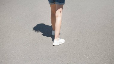 Beyaz ayakkabılı bir kadın dışarıda yürüyor..