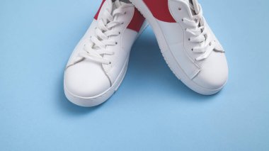 Mavi arka planda beyaz spor ayakkabılar.