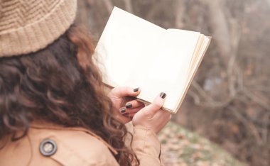 Sonbahar parkında kitap okuyan bir kız..