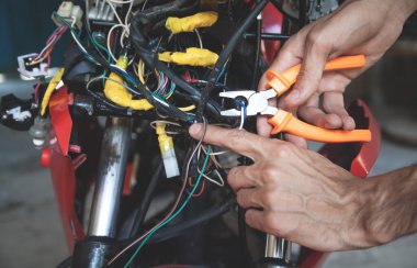 İşçi kerpetenle elektrik kablosu kesiyor.
