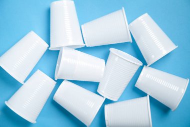 Mavi arkaplanda tek kullanımlık beyaz bardaklar..