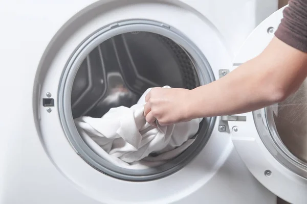 Çamaşır makinesine çarşaf koyan kız.