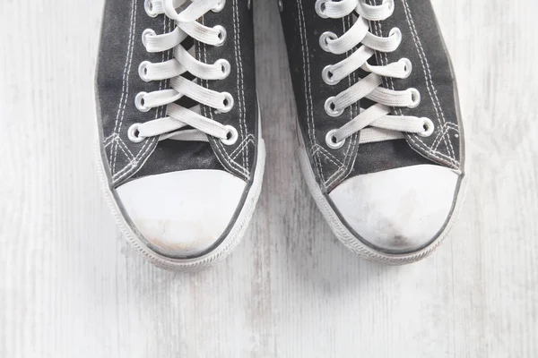 Beyaz masada bir çift eski kirli ayakkabı..