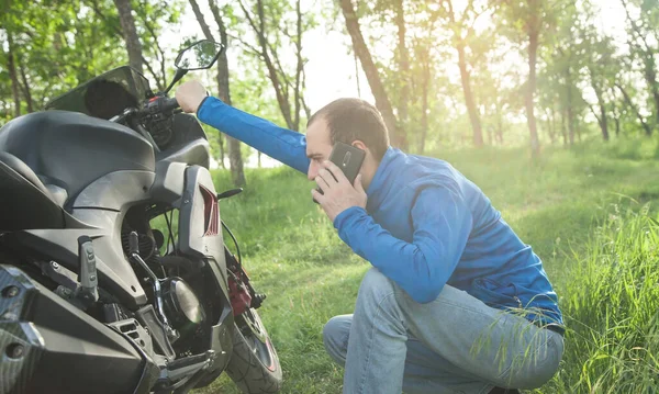 Motorcu doğada akıllı telefonla konuşuyor..