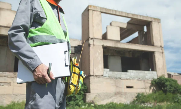 Kalem ve pano tutan inşaat işçisi.