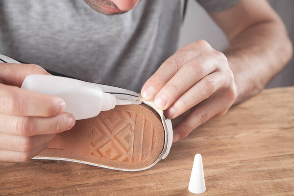 Man fixing sneakers with a glue.