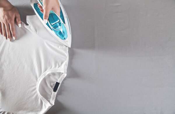 Young girl ironing t-shirt in home.