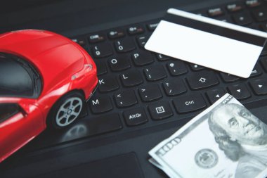 Klavyede kredi kartı, dolar ve kırmızı oyuncak araba..