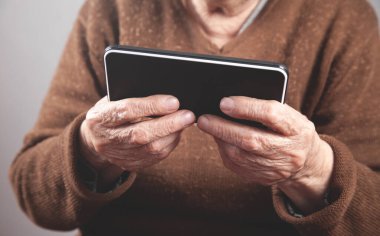 Beyaz, yaşlı bir kadın akıllı telefon kullanıyor..