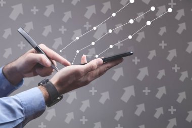 İşadamı grafikleri, okları ve sembolleri olan akıllı telefon kullanıyor..