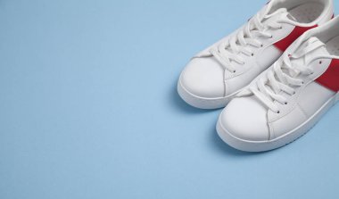 Mavi arka planda beyaz spor ayakkabılar.