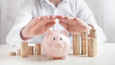 İşadamı domuz kumbarasını ve sikkeleri korur. Para biriktiriliyor 