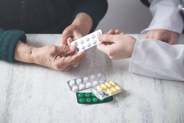 Doktor yaşlı kadına hap veriyor..