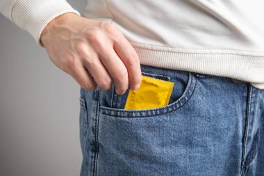 Beyaz adam prezervatif gösteriyor. Güvenli seks.