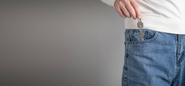 Kot pantolon cebinden evin anahtarlarını gösteren bir adam. Emlak